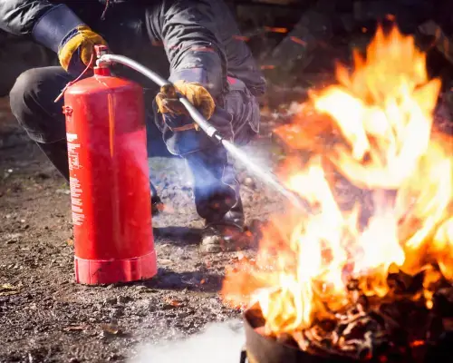 person putting out a small fire with extinguisher