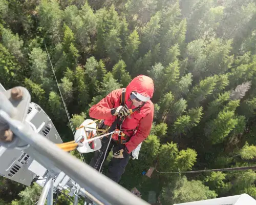 man harnessed on side of a structure